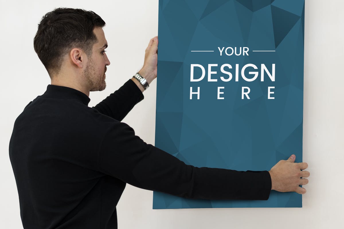 手持海报艺术创作设计样机模板 A man hanging photo frame on wall Mockup